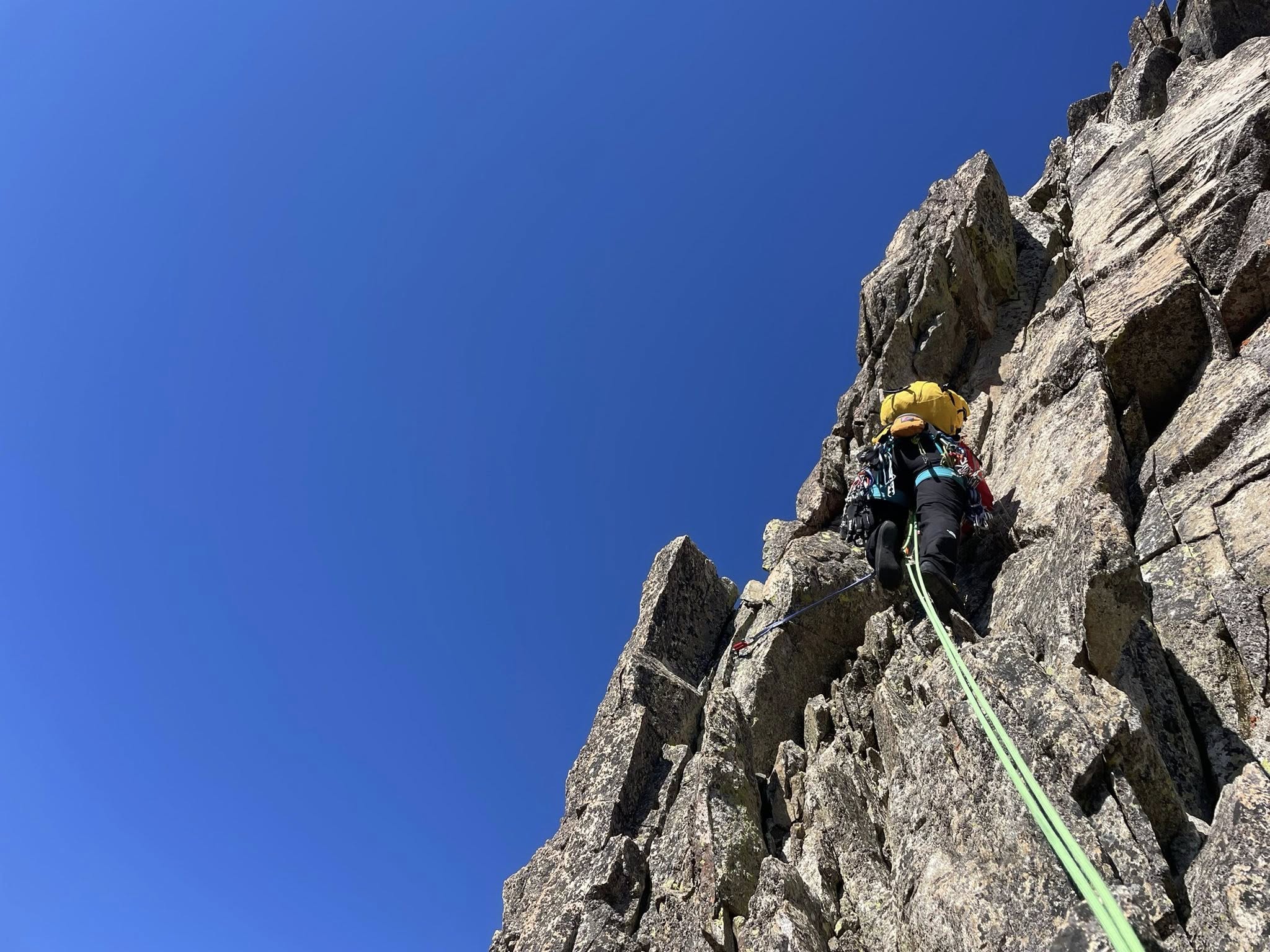 Alpinista escalando en roca natural asegurado con cuerda